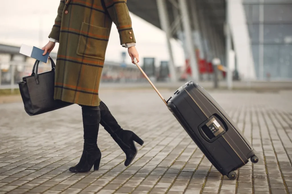 2027 Resmi Tatiller ve 5 Güne 35 Gün Tatil Yapma Planı 3 Havalimanında valiz sapına konmuş pasaport ve arkada flu ekran